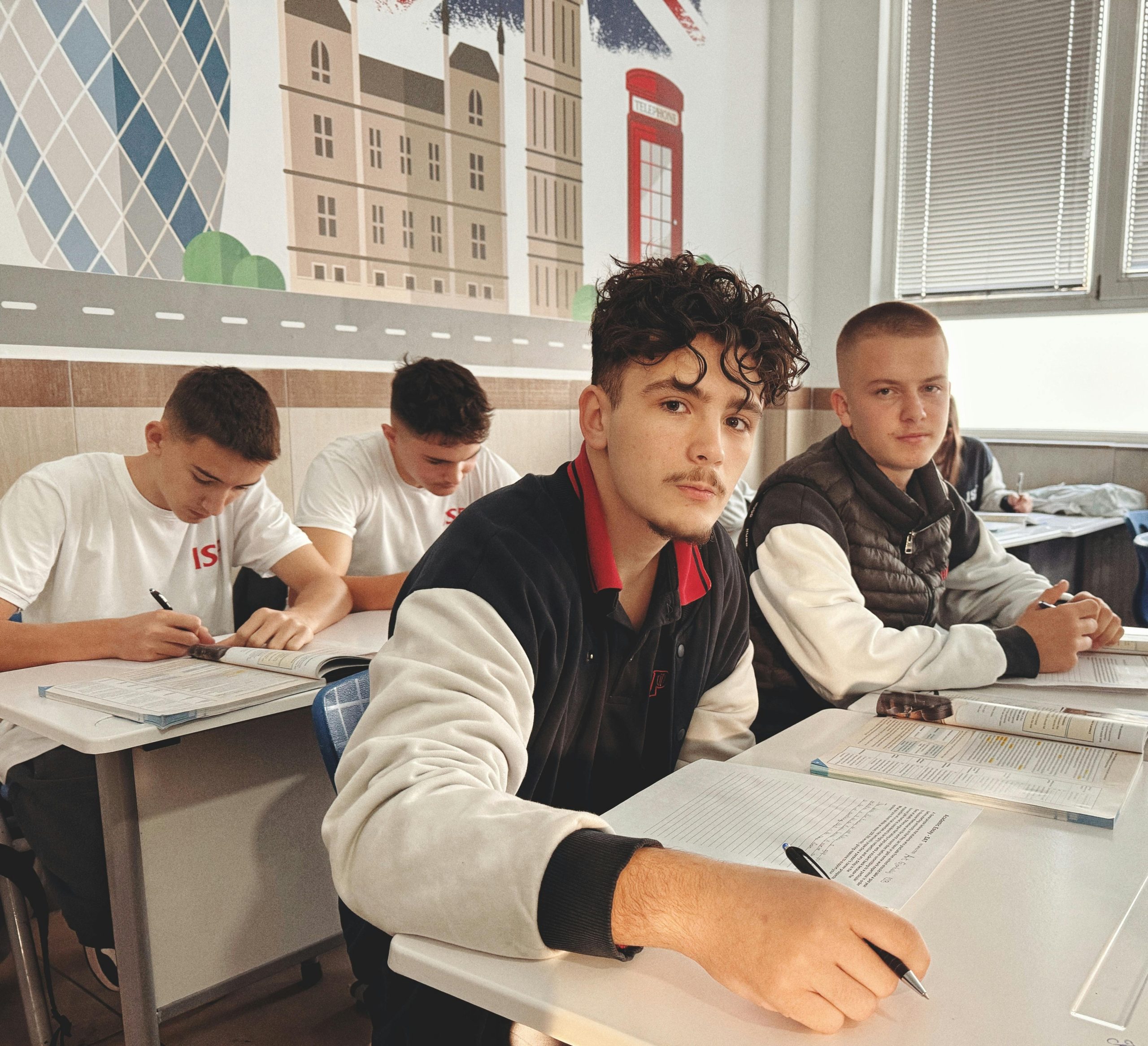 High school students studying in a classroom featuring British-themed wall art.